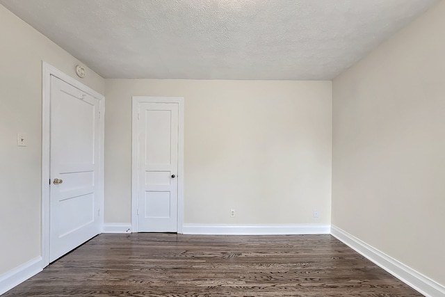 unfurnished room featuring a textured ceiling and dark hardwood / wood-style flooring