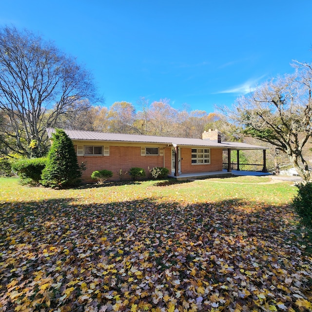 rear view of property with a carport and a yard