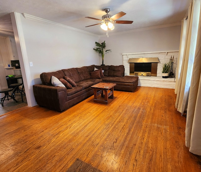 living room featuring a fireplace, hardwood / wood-style flooring, ceiling fan, and crown molding