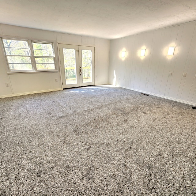 empty room featuring french doors, carpet, and a textured ceiling