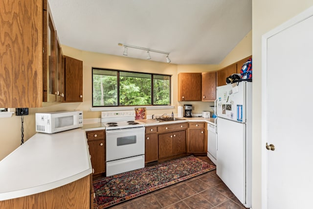 kitchen featuring lofted ceiling, dark tile patterned floors, white appliances, and sink