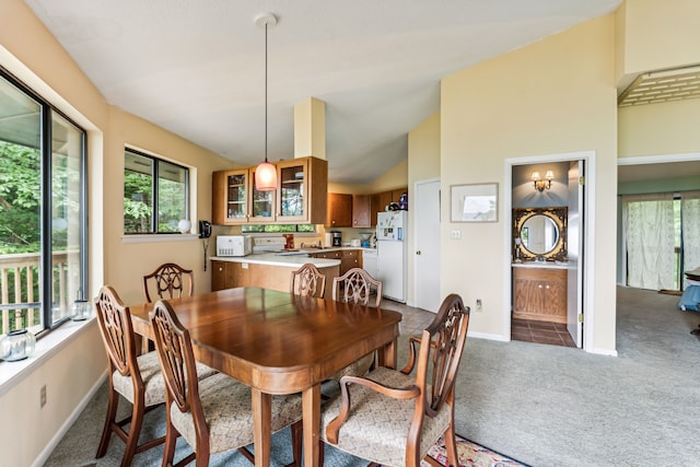 carpeted dining space with vaulted ceiling