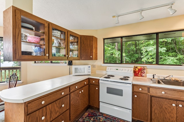 kitchen with kitchen peninsula, rail lighting, a textured ceiling, white appliances, and sink