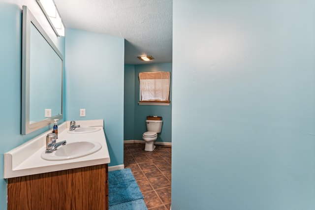 bathroom featuring tile patterned floors, vanity, toilet, and a textured ceiling