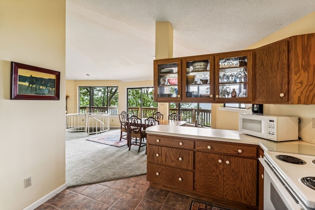 kitchen featuring a textured ceiling, white appliances, high vaulted ceiling, and dark tile patterned floors