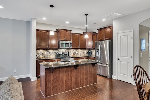 kitchen featuring pendant lighting, a center island with sink, sink, dark hardwood / wood-style floors, and appliances with stainless steel finishes