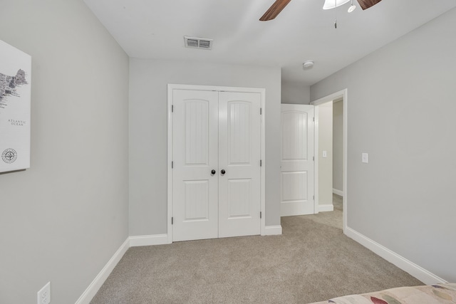 unfurnished bedroom featuring ceiling fan, a closet, and light carpet