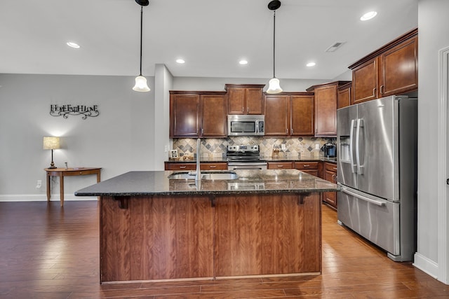 kitchen featuring stainless steel appliances, a kitchen island with sink, and dark hardwood / wood-style floors