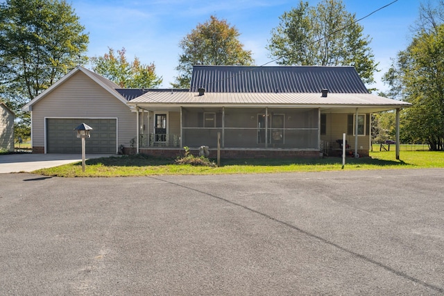 view of front of house with a garage, a front yard, and a sunroom