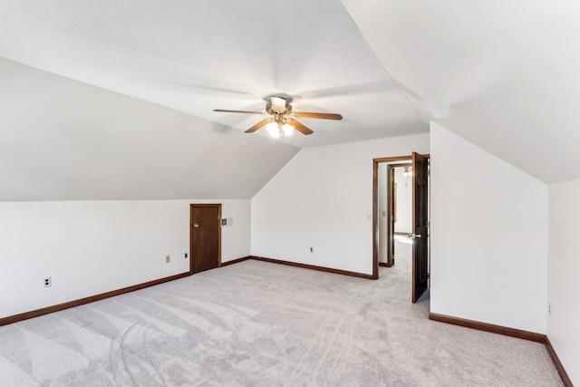 additional living space with light colored carpet, vaulted ceiling, and ceiling fan