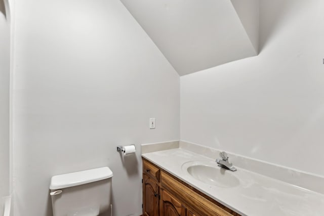 bathroom featuring toilet, vaulted ceiling, and vanity