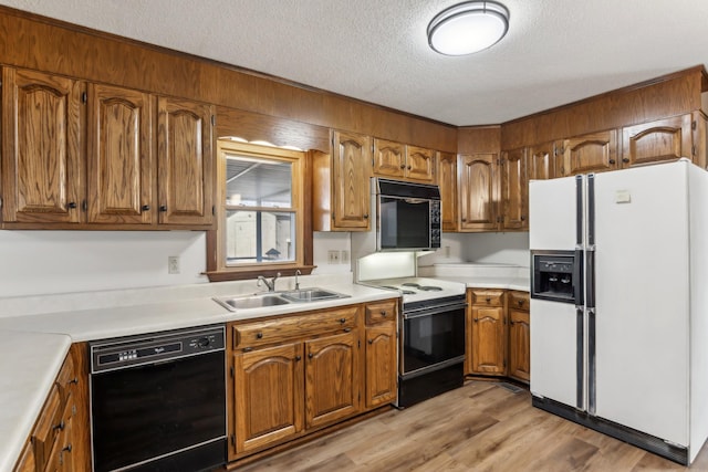 kitchen with light hardwood / wood-style floors, sink, a textured ceiling, and black appliances