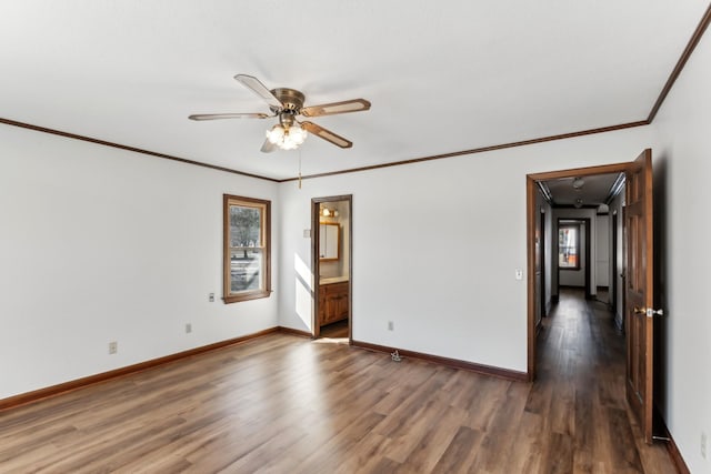 spare room featuring crown molding, a healthy amount of sunlight, dark hardwood / wood-style floors, and ceiling fan