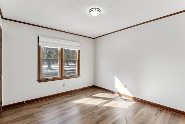 empty room with hardwood / wood-style flooring, ornamental molding, and a textured ceiling