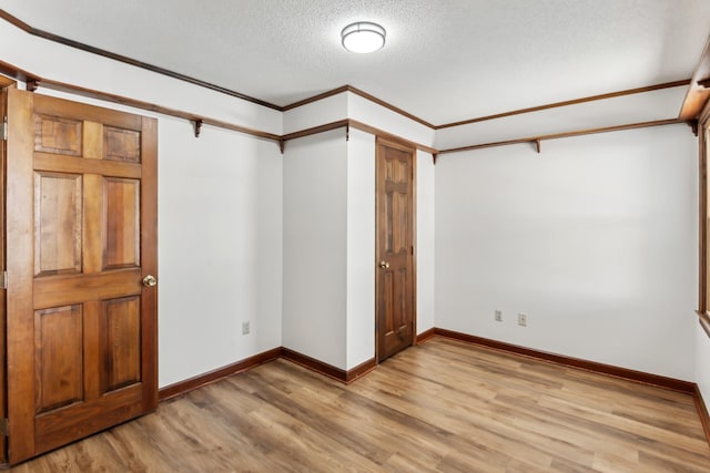 unfurnished bedroom featuring a textured ceiling, ornamental molding, and light wood-type flooring