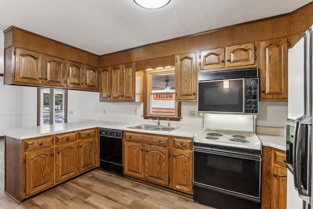 kitchen with black appliances, a textured ceiling, light wood-type flooring, sink, and kitchen peninsula