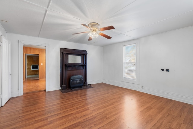 unfurnished living room with hardwood / wood-style floors, ceiling fan, and a wood stove