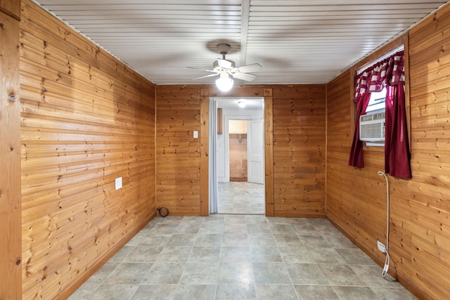 empty room featuring cooling unit, wood walls, and ceiling fan