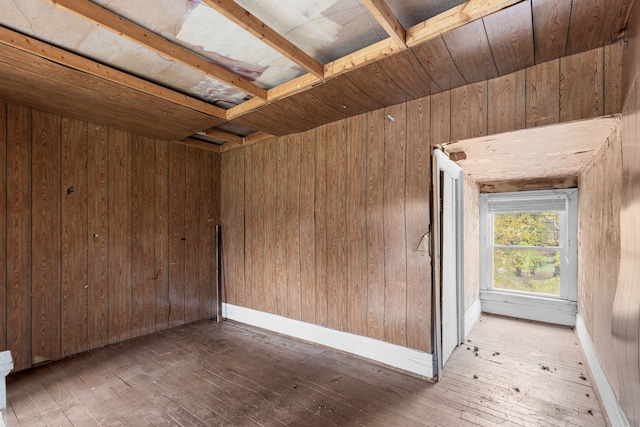 spare room featuring wooden walls and light hardwood / wood-style flooring