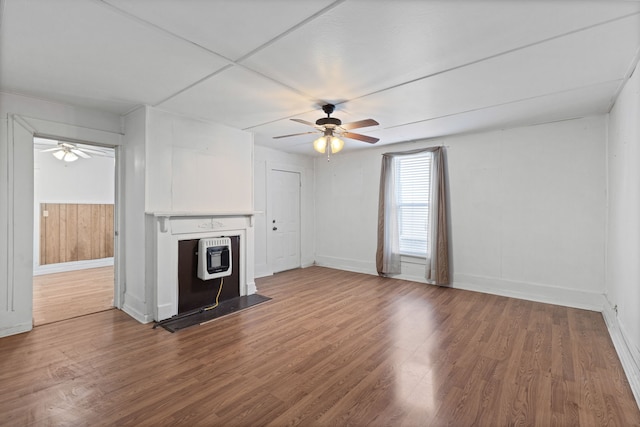 unfurnished living room with heating unit, ceiling fan, and wood-type flooring