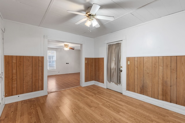 spare room featuring wood walls, ceiling fan, and light hardwood / wood-style floors