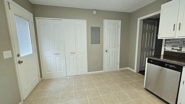 kitchen featuring light tile patterned floors, white cabinetry, stainless steel dishwasher, and plenty of natural light