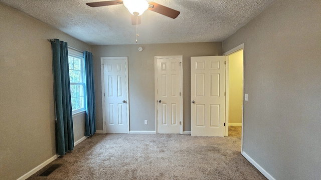 unfurnished bedroom with carpet flooring, a textured ceiling, and ceiling fan