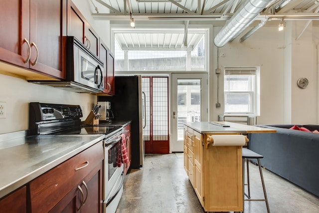 kitchen with stainless steel counters, rail lighting, white electric range oven, a kitchen breakfast bar, and a kitchen island