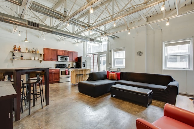 living room with plenty of natural light, a towering ceiling, and bar area