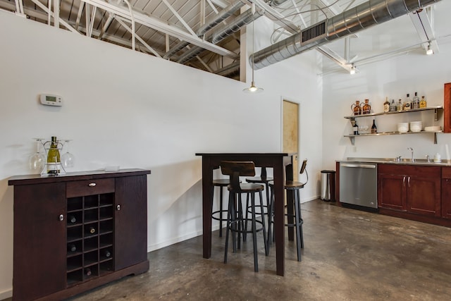 bar with sink, stainless steel dishwasher, and a high ceiling