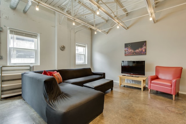 living room with plenty of natural light, concrete flooring, and a high ceiling