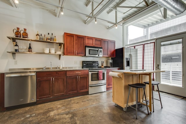 kitchen featuring stainless steel counters, sink, stainless steel appliances, a kitchen breakfast bar, and a kitchen island