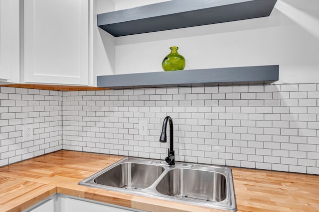 kitchen featuring wooden counters, decorative backsplash, sink, wood-type flooring, and white cabinets