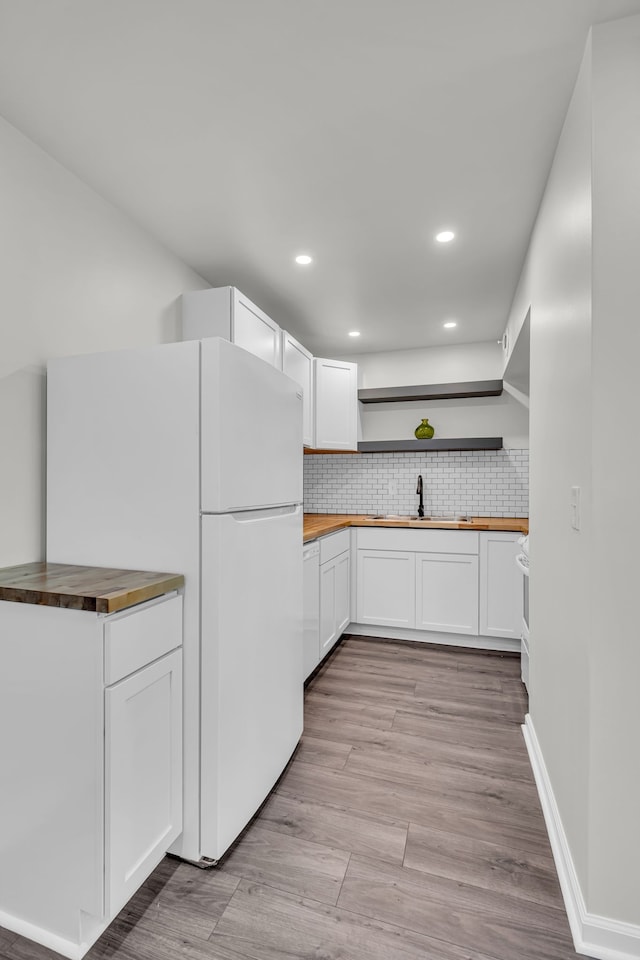 kitchen featuring white appliances, sink, light hardwood / wood-style flooring, butcher block countertops, and white cabinetry