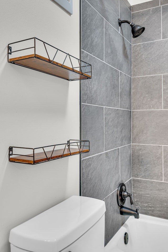 bathroom featuring tiled shower / bath combo and toilet