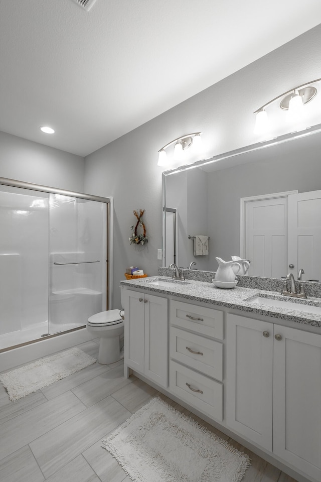 bathroom with vanity, a shower with shower door, and toilet