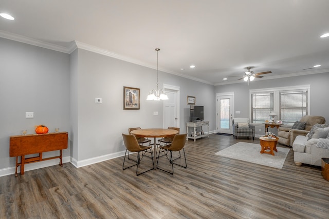 dining area with ornamental molding, ceiling fan with notable chandelier, and dark wood-type flooring