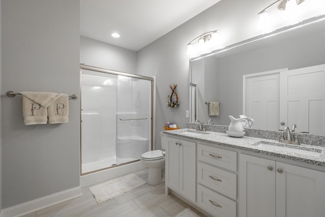 bathroom featuring a shower with door, vanity, and toilet