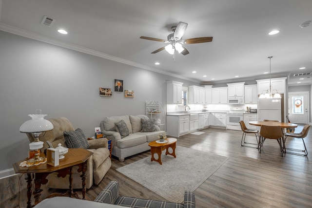 living room with dark hardwood / wood-style floors, ceiling fan with notable chandelier, and ornamental molding