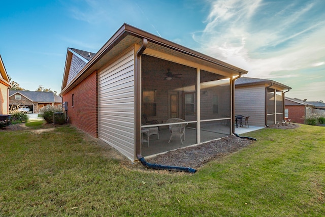 view of side of property featuring a sunroom, ceiling fan, a patio area, and a yard