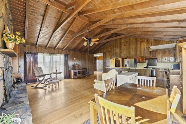 dining area featuring wooden walls, light hardwood / wood-style flooring, ceiling fan, beamed ceiling, and wood ceiling