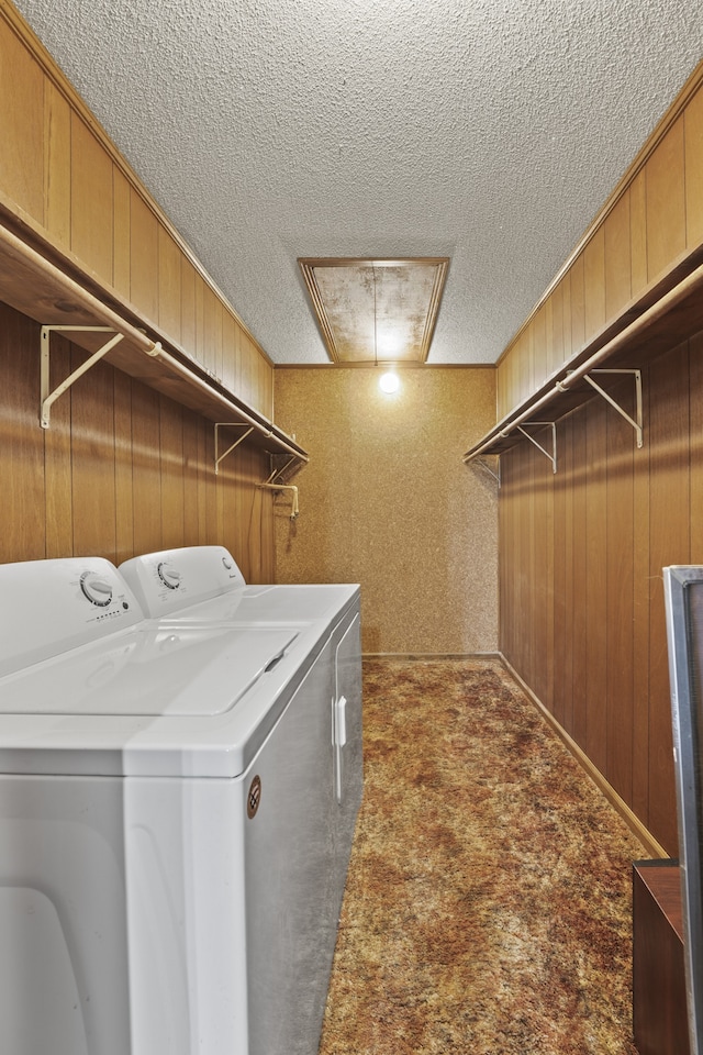 laundry area with carpet flooring, separate washer and dryer, wood walls, and a textured ceiling