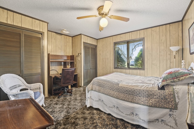 bedroom featuring a textured ceiling, ceiling fan, and wood walls