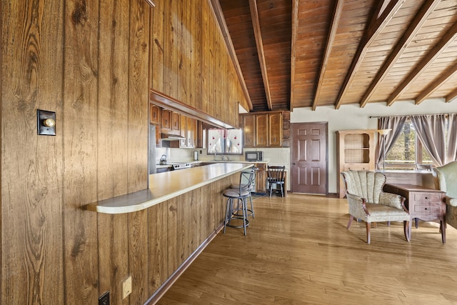 kitchen featuring wood walls, wooden ceiling, light wood-type flooring, a kitchen bar, and kitchen peninsula