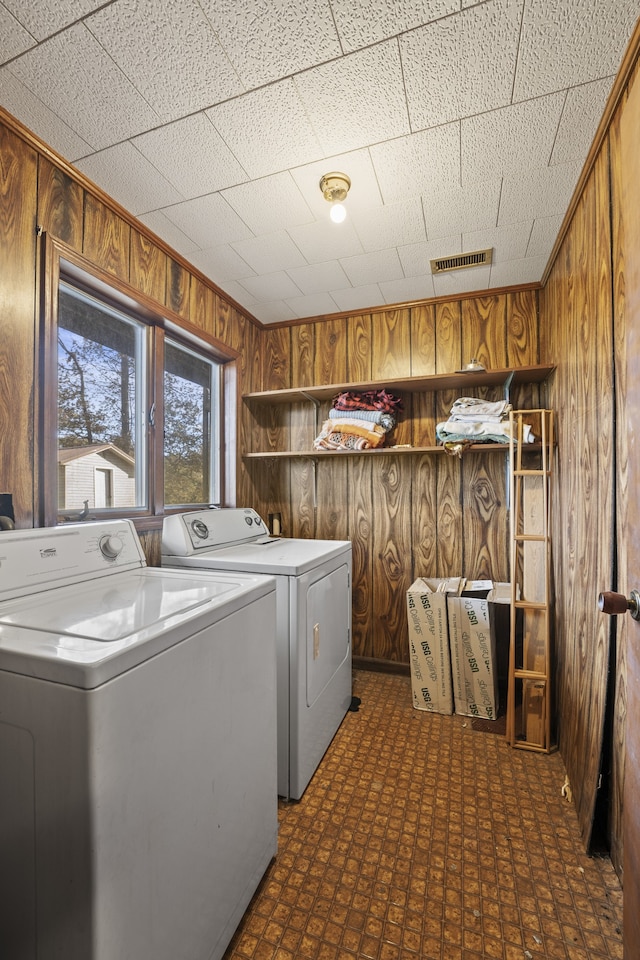 washroom featuring wood walls and washing machine and dryer