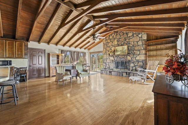 unfurnished living room featuring ceiling fan, light hardwood / wood-style flooring, wooden ceiling, a fireplace, and vaulted ceiling with beams