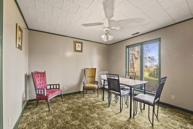 dining area featuring wood walls, crown molding, and ceiling fan