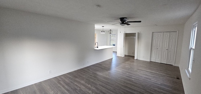 unfurnished bedroom featuring multiple closets, ceiling fan, sink, dark wood-type flooring, and a textured ceiling