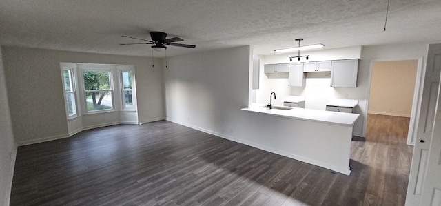 kitchen featuring a textured ceiling, decorative light fixtures, sink, and dark wood-type flooring