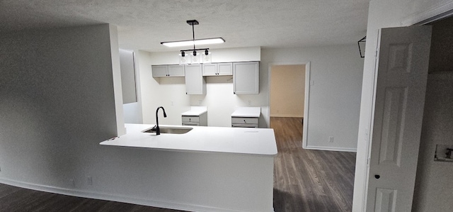 kitchen with sink, dark wood-type flooring, hanging light fixtures, a textured ceiling, and gray cabinets